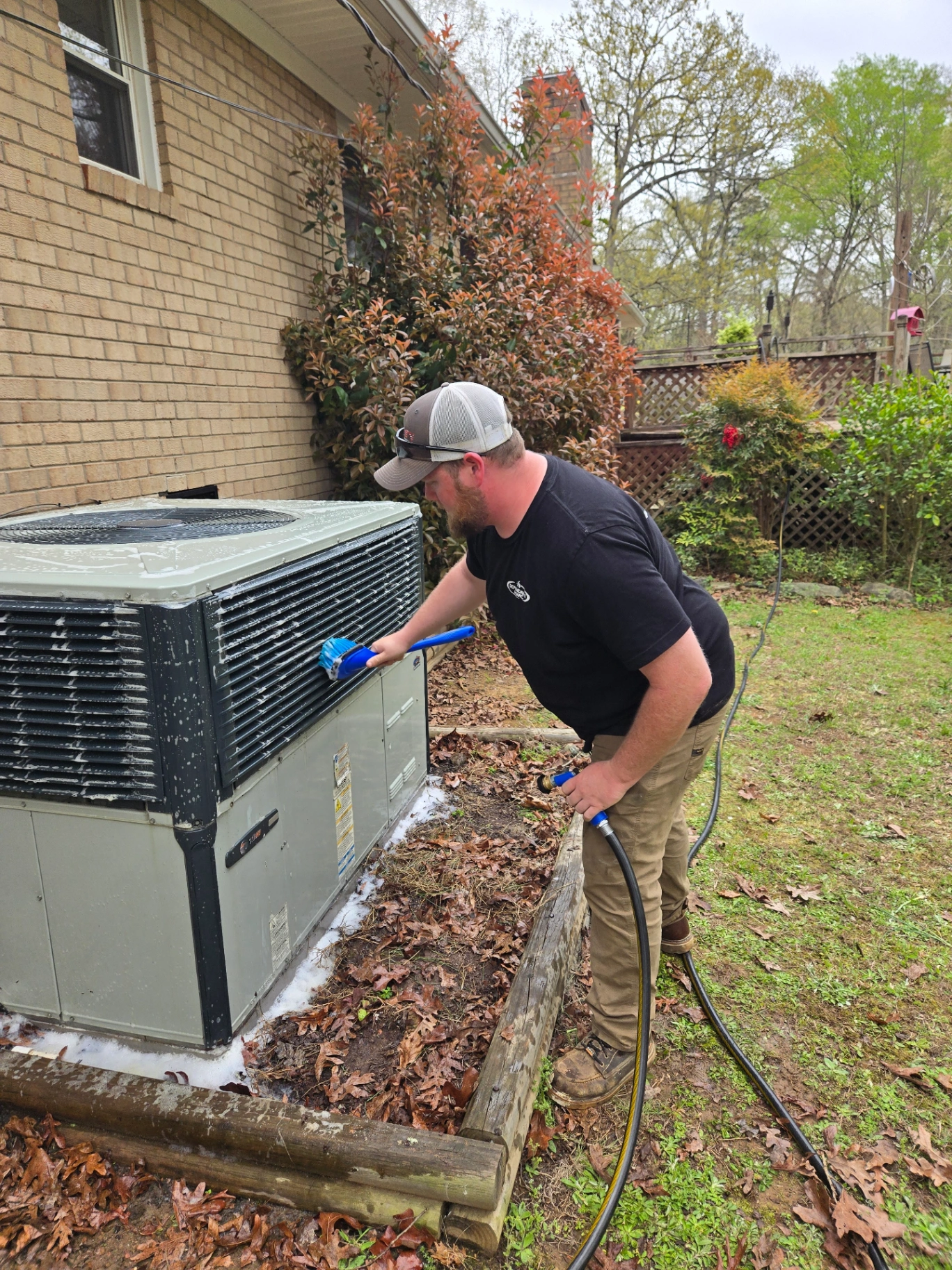 Dependable HVAC technician cleaning outdoor unit in Woodrun